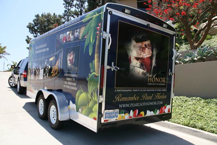 Rear trailer door showing the proposed cover of the book Pearls of Honor: Their Duty to Remember, framed by palm trees and hibiscus flowers