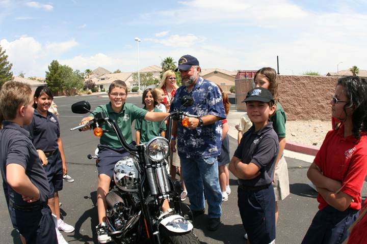 Elementary school children crowding around the tribute motorcycle