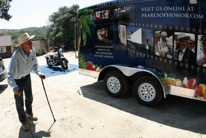 John Finn in his cowboy hat inspecting the wrapped trailer that carries the bike