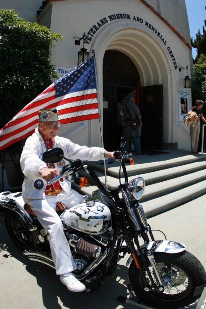 Pearl Harbor Survivor Stu Hedley grinning while sitting on Metal of Honor